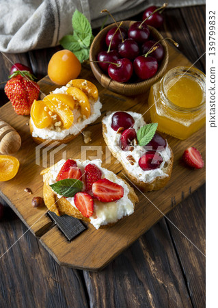 Assorted bruschetta with ricotta, honey, cherries, apricot and strawberry on a rustic table. Berries toast summer breakfast, healthy food. Copy space. 139799832