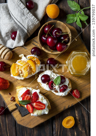 Assorted bruschetta with ricotta, honey, cherries, apricot and strawberry on a rustic table. Berries toast summer breakfast, healthy food. View from above. Copy space. 139799837