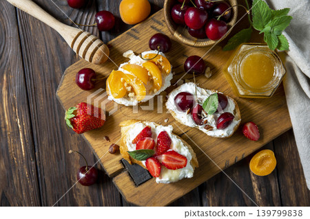 Assorted bruschetta with ricotta, honey, cherries, apricot and strawberry on a rustic table. Berries toast summer breakfast, healthy food. View from above. Copy space. 139799838