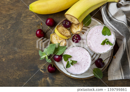 Pink cherries and banana fruit smoothie or milk protein shake on stone tabletop. Yogurt cocktail, natural detox. Liquid ice cream. View from above. Pink cherries and banana fruit smoothie or milk protein shake on stone tabletop. Yogurt cocktail, natural detox. Liquid ice cream. View from above. 139799861