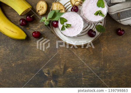 Cherries and banana fruit smoothie or milk protein shake on stone tabletop. Yogurt cocktail, natural detox. Liquid ice cream. View from above. Copy space. Cherries and banana fruit smoothie or milk protein shake on stone tabletop. Yogurt cocktail, natural detox. Liquid ice cream. View from above. Copy space. 139799863
