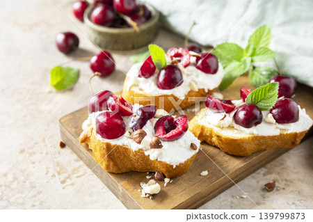 Bruschetta with ricotta, cherry and nuts on a stone tabletop. Berries toast summer breakfast, healthy food. 139799873