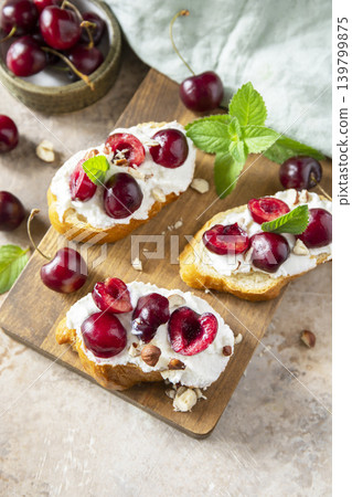 Bruschetta with ricotta, cherry and nuts on a stone tabletop. Berries toast summer breakfast, healthy food. Copy space. 139799875