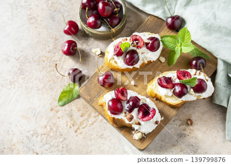Bruschetta with ricotta, cherry and nuts on a stone tabletop. Berries toast summer breakfast, healthy food. Copy space. Bruschetta with ricotta, cherry and nuts on a stone tabletop. Berries toast summer breakfast, healthy food. Copy space. 139799876