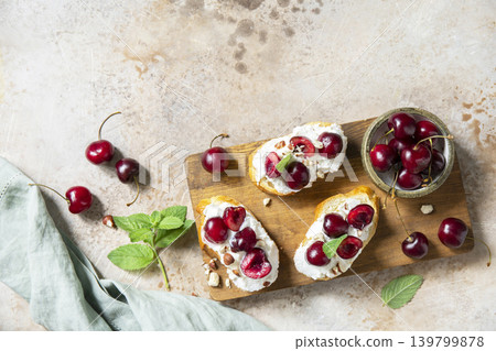Bruschetta with ricotta, cherry and nuts on a stone tabletop. Berries toast summer breakfast, healthy food. View from above. Copy space. 139799878