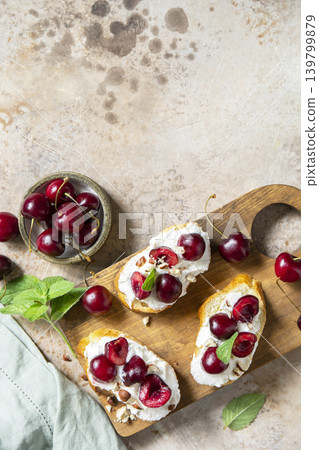 Bruschetta with ricotta, cherry and nuts on a stone tabletop. Berries toast summer breakfast, healthy food. View from above. Copy space. Bruschetta with ricotta, cherry and nuts on a stone tabletop. Berries toast summer breakfast, healthy food. View from above. Copy space. 139799879