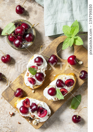 Bruschetta with ricotta, cherry and nuts on a stone tabletop. Berries toast summer breakfast, healthy food. View from above. 139799880