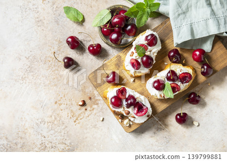 Bruschetta with ricotta, cherry and nuts on a stone tabletop. Berries toast summer breakfast, healthy food. View from above. 139799881