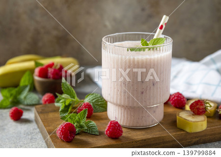 Pink raspberries and banana fruit smoothie or milk protein shake on stone tabletop. Yogurt cocktail, natural detox. Liquid ice cream. Copy space. Pink raspberries and banana fruit smoothie or milk protein shake on stone tabletop. Yogurt cocktail, natural detox. Liquid ice cream. Copy space. 139799884