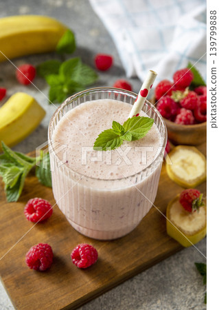 Pink raspberries and banana fruit smoothie or milk protein shake on stone tabletop. Yogurt cocktail, natural detox. Liquid ice cream. Pink raspberries and banana fruit smoothie or milk protein shake on stone tabletop. Yogurt cocktail, natural detox. Liquid ice cream. 139799888