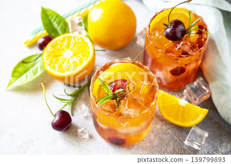 Refreshing summer cherry and orange cocktail cola lemonade or mojito cocktail in glass with ice and mint on stone tabletop. Refreshing summer cherry and orange cocktail cola lemonade or mojito cocktail in glass with ice and mint on stone tabletop. 139799893