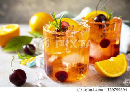 Refreshing summer cherry and orange cocktail cola lemonade or mojito cocktail in glass with ice and mint close up on stone tabletop. Refreshing summer cherry and orange cocktail cola lemonade or mojito cocktail in glass with ice and mint close up on stone tabletop. 139799894