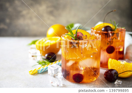 Refreshing summer cherry and orange cocktail cola lemonade or mojito cocktail in glass with ice and mint on stone tabletop. Copy space. Refreshing summer cherry and orange cocktail cola lemonade or mojito cocktail in glass with ice and mint on stone tabletop. Copy space. 139799895