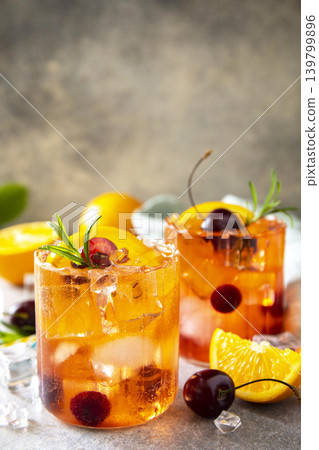 Refreshing summer cherry and orange cocktail cola lemonade or mojito cocktail in glass with ice and mint on stone tabletop. Copy space. 139799896