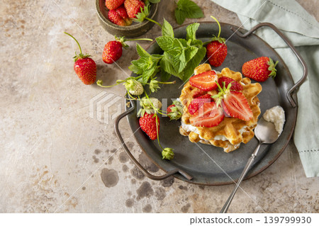 Belgian waffles with ricotta cheese and fresh strawberries for breakfast on a stone background. Sweet breakfast gluten free. Summer homemade recipe. Copy space. Belgian waffles with ricotta cheese and fresh strawberries for breakfast on a stone background. Sweet breakfast gluten free. Summer homemade recipe. Copy space. 139799930