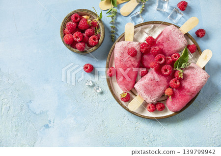 Healthy summer food concept, homemade raspberry ice cream. Vegan raspberry milk popsicles on a blue stone background. View from above. Healthy summer food concept, homemade raspberry ice cream. Vegan raspberry milk popsicles on a blue stone background. View from above. 139799942