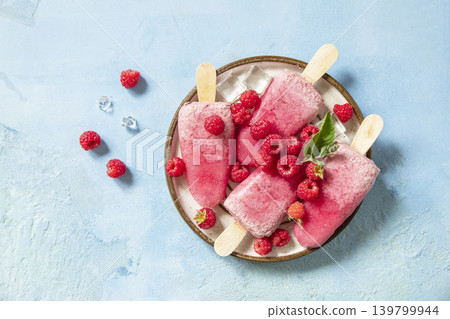 Healthy summer food concept, homemade raspberry ice cream. Vegan raspberry milk popsicles on a blue stone background. View from above. Healthy summer food concept, homemade raspberry ice cream. Vegan raspberry milk popsicles on a blue stone background. View from above. 139799944