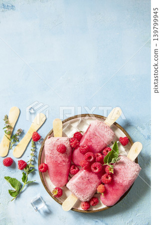 Healthy summer food concept, homemade raspberry ice cream. Vegan raspberry milk popsicles on a blue stone background. View from above. Copy space. Healthy summer food concept, homemade raspberry ice cream. Vegan raspberry milk popsicles on a blue stone background. View from above. Copy space. 139799945