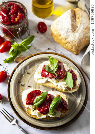 Open sandwiches or bruschetta with cream cheese and sun dried tomatoes on a stone table. Healthy food. Delicious breakfast or wine snack. Open sandwiches or bruschetta with cream cheese and sun dried tomatoes on a stone table. Healthy food. Delicious breakfast or wine snack. 139799956