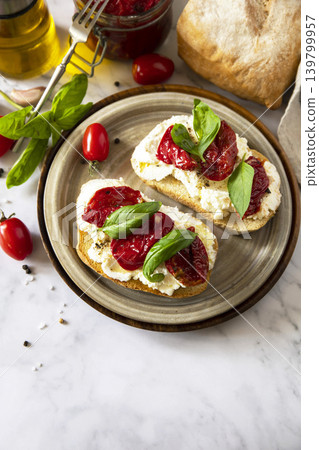 Open sandwiches or bruschetta with cream cheese and sun dried tomatoes on a stone table. Healthy food. Delicious breakfast or wine snack. Copy space. Open sandwiches or bruschetta with cream cheese and sun dried tomatoes on a stone table. Healthy food. Delicious breakfast or wine snack. Copy space. 139799957