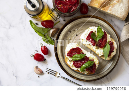 Open sandwiches or bruschetta with cream cheese and sun dried tomatoes on a stone table. Healthy food. Delicious breakfast or wine snack. Copy space. Open sandwiches or bruschetta with cream cheese and sun dried tomatoes on a stone table. Healthy food. Delicious breakfast or wine snack. Copy space. 139799958