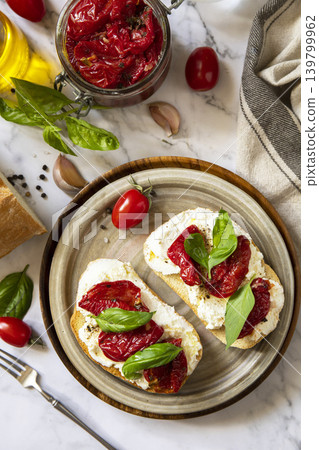Open sandwiches or bruschetta with cream cheese and sun dried tomatoes on a stone table. Healthy food. Delicious breakfast or wine snack. View from above. Open sandwiches or bruschetta with cream cheese and sun dried tomatoes on a stone table. Healthy food. Delicious breakfast or wine snack. View from above. 139799962