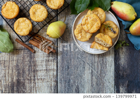 Homemade biscuit cakes sweet cottage cheese muffins with pear, cinnamon on a rustic wooden tabletop. Autumn vegetarian baking. View from above. Copy space. Homemade biscuit cakes sweet cottage cheese muffins with pear, cinnamon on a rustic wooden tabletop. Autumn vegetarian baking. View from above. Copy space. 139799971