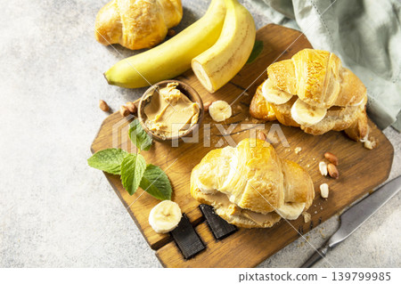 French pastry, freshly baked croissants with peanut butter and banana on a grey stone background. Healthy food dessert concept. Copy space. French pastry, freshly baked croissants with peanut butter and banana on a grey stone background. Healthy food dessert concept. Copy space. 139799985