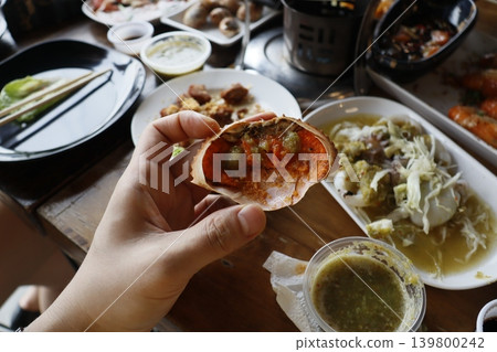 Hand Holding Crab Shell with Food in Restaurant Setting 139800242
