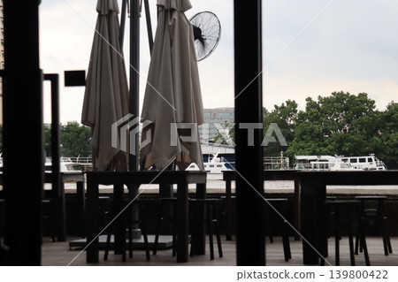 Riverfront Cafe Seating with Umbrellas and Boats 139800422