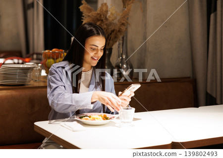 Woman enjoying social media connection during restaurant dinner Woman enjoying social media connection during restaurant dinner 139802493