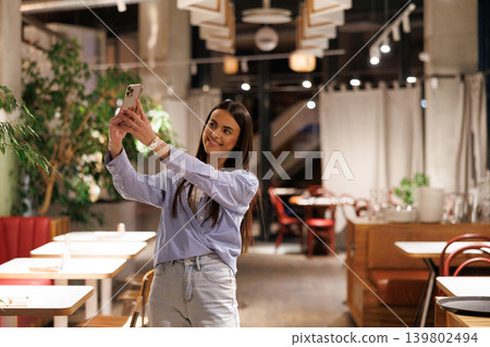 Young woman taking selfie with smartphone in restaurant Young woman taking selfie with smartphone in restaurant 139802494