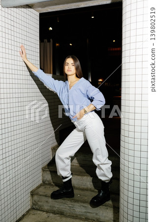 Woman posing in blue striped shirt and white pants Woman posing in blue striped shirt and white pants 139802519