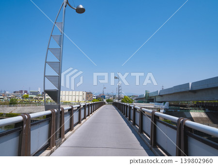 A walkway on a bridge lined with modern streetlights; an urban promenade. A walkway on a bridge lined with modern streetlights; an urban promenade. 139802960