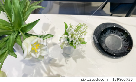 Elegant table setting with modern black plates and fresh white tulips casting shadows on marble surface Elegant table setting with modern black plates and fresh white tulips casting shadows on marble surface 139803736