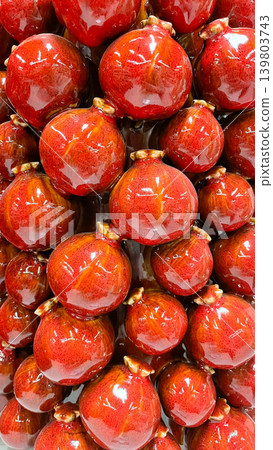 Macro background of sweet red glazed pomegranates with a vibrant glossy texture and rich color Macro background of sweet red glazed pomegranates with a vibrant glossy texture and rich color 139803743