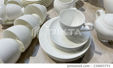 Minimalist white porcelain tea set featuring stacked cups and plates for an elegant table setting 139803755