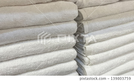 Perfectly folded stacks of clean white terry towels for a minimalist luxury spa and hotel aesthetic Perfectly folded stacks of clean white terry towels for a minimalist luxury spa and hotel aesthetic 139803759