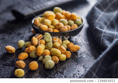 Crunchy Wasabi Peas and Coated Peanuts in a Bowl - Spicy Snack Mix on Dark Surface Crunchy Wasabi Peas and Coated Peanuts in a Bowl - Spicy Snack Mix on Dark Surface 139803851