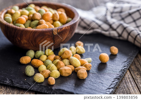 Close-Up Bowl of Coated Peanuts and Crunchy Snack Mix in a Rustic Dark Setting Close-Up Bowl of Coated Peanuts and Crunchy Snack Mix in a Rustic Dark Setting 139803856