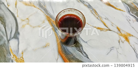 A glass of coffee on a gold-patterned marble floor 139804915