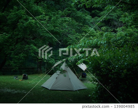 Standing amidst the tranquility of fresh greenery: A solo campsite and tipi tent by the lake. 139804985