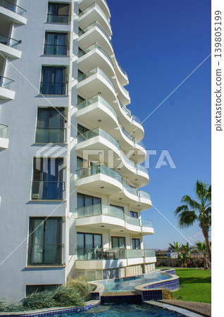 Modern coastal apartment building with curvy balconies and a clear blue sky in a sunny location. 139805199