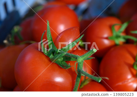 Vibrant red tomatoes gleaming under the sun in a vibrant farmer's market display filled with fresh produce and earthy aromas Vibrant red tomatoes gleaming under the sun in a vibrant farmer's market display filled with fresh produce and earthy aromas 139805223