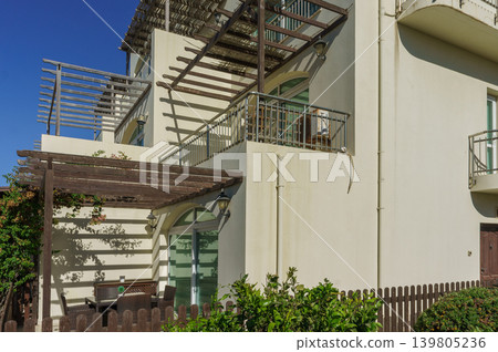 A beautiful modern house with a terrace under a clear blue sky in a tranquil neighborhood. A beautiful modern house with a terrace under a clear blue sky in a tranquil neighborhood. 139805236