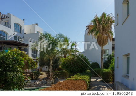 Sunny day in a tranquil residential complex with lush gardens and palm trees. 139805248
