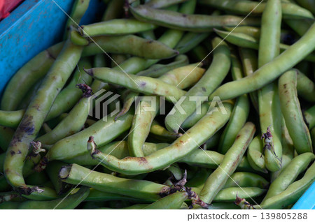 Fresh green fava beans piled high in a rustic market basket during the vibrant farmers market Fresh green fava beans piled high in a rustic market basket during the vibrant farmers market 139805288