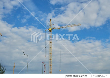 Low angle view of heavy lifting equipment and concrete building structure under development on a bright daytime Low angle view of heavy lifting equipment and concrete building structure under development on a bright daytime 139805626