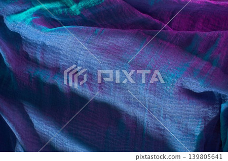 Colorful fabric draped softly on a surface showing various shades of purple and blue in natural light Colorful fabric draped softly on a surface showing various shades of purple and blue in natural light 139805641