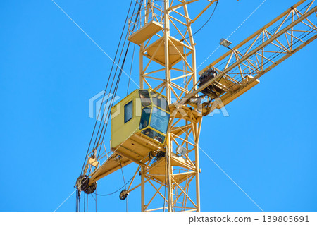 A tall construction crane is seen working under a clear blue sky 139805691